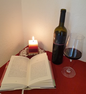 eine Flasche wein bei Kerzenschein und ein Buch